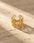 Model wearing gold chain link cuff ring on silk fabric