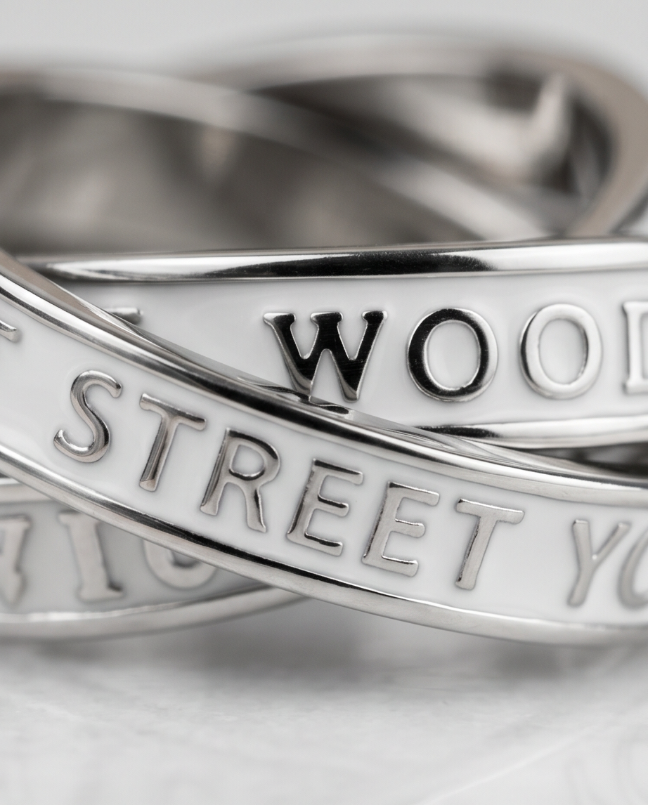 Macro close-up of raised serif engraved lettering on polished silver interlocking bands