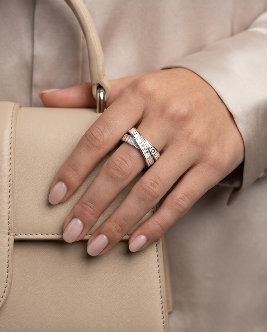 Model wearing silver triple interlocking text band ring holding beige luxury handbag