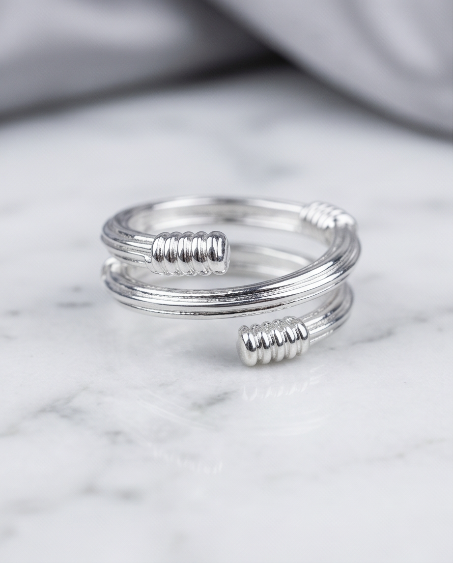 Silver coil wrap ribbed end open ring in grey velvet jewellery box on marble