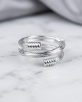 Silver coil wrap ribbed end open ring in grey velvet jewellery box on marble