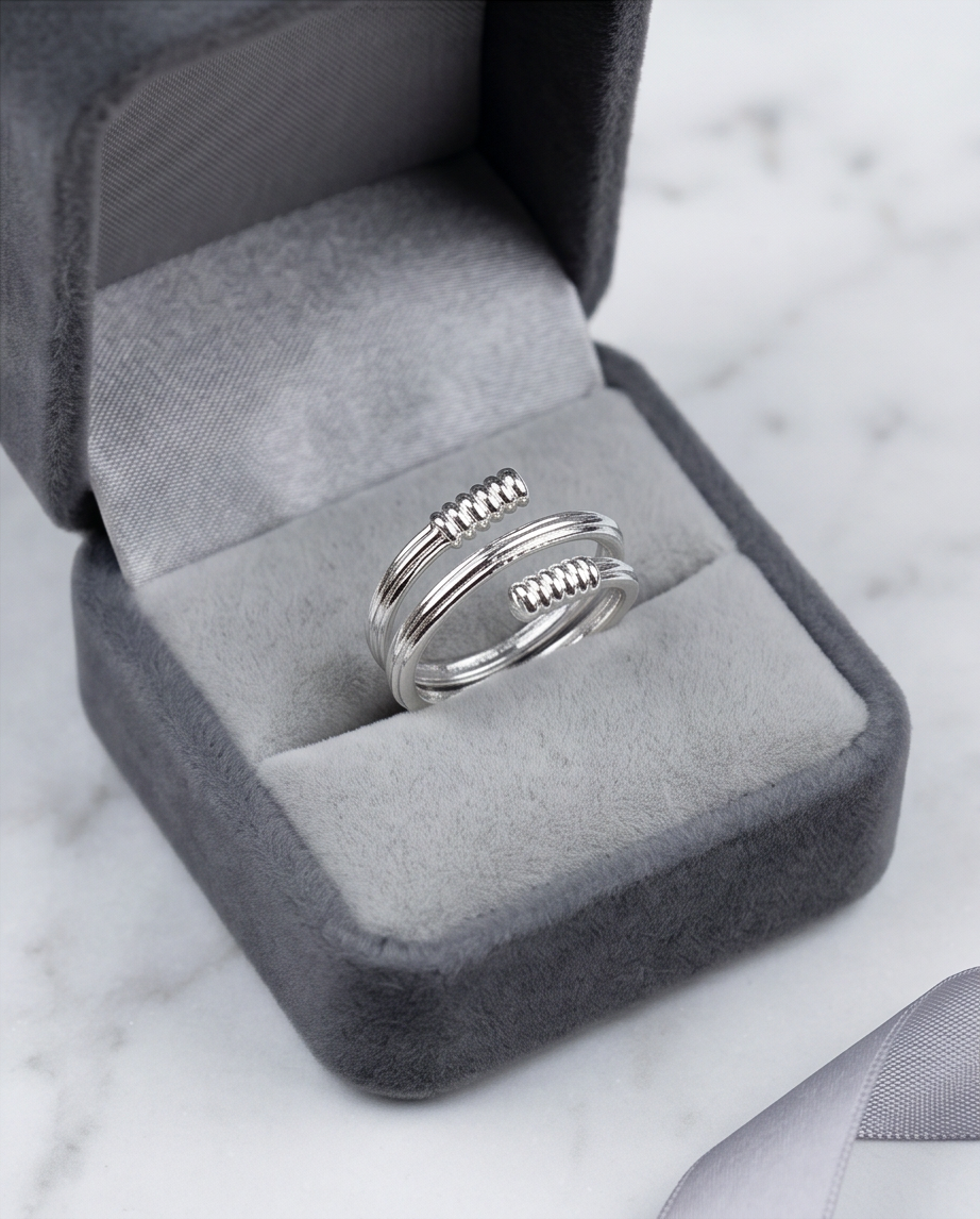 Silver coil wrap ribbed end open ring on marble surface with grey ribbon