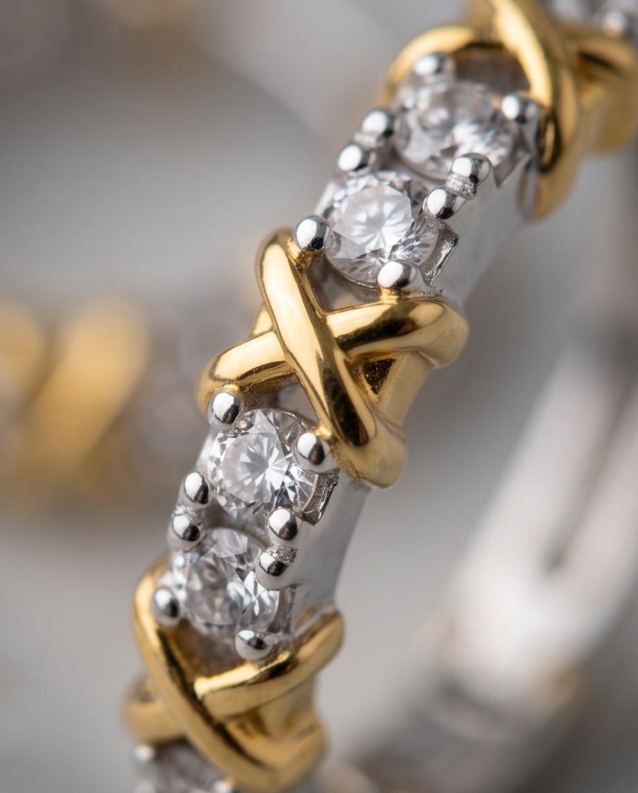 Gold X cross cubic zirconia hoop earrings pair on marble