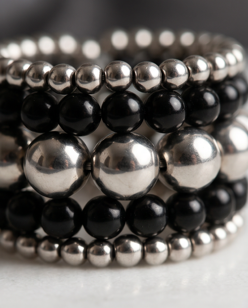 Black Onyx & Silver Bead Stacked Wide Band Ring worn on white female hand resting on grey velvet chair
