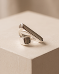 Macro close up of 925 silver plated high polish geometric bar and square signet wrap open adjustable ring showing mirror-finish elongated bar and square signet detail against warm beige background