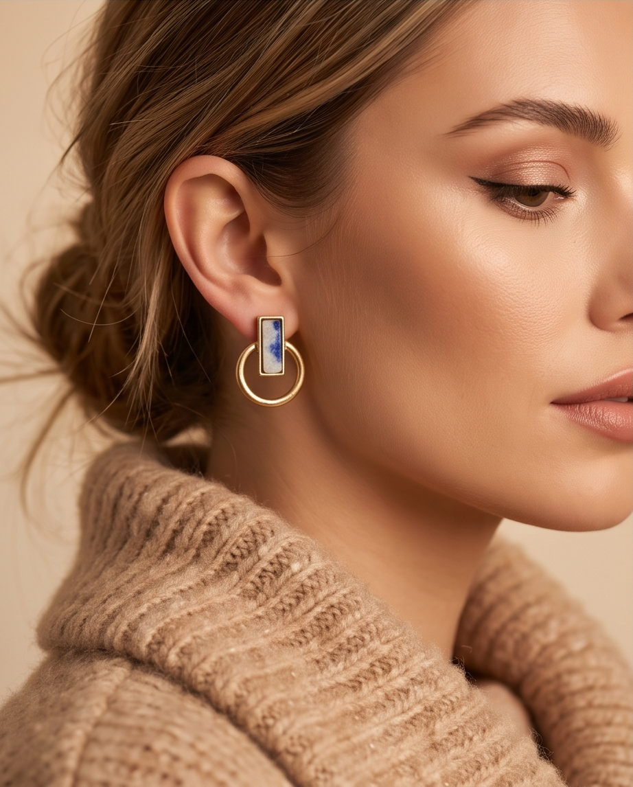 Model in camel turtleneck with loose updo wearing gold tone matte sodalite blue marble rectangle bezel open circle hoop drop earring in warm neutral portrait