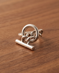 925 silver plated high polish celtic love knot circle toggle bar open adjustable ring on warm walnut wood surface in natural light showing full profile and toggle bar pendant