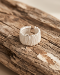 925 silver plated granular textured wide cuff open adjustable ring on green forest moss with smooth pebbles — nature editorial macro product shot showing full granular bead texture and scalloped edge
