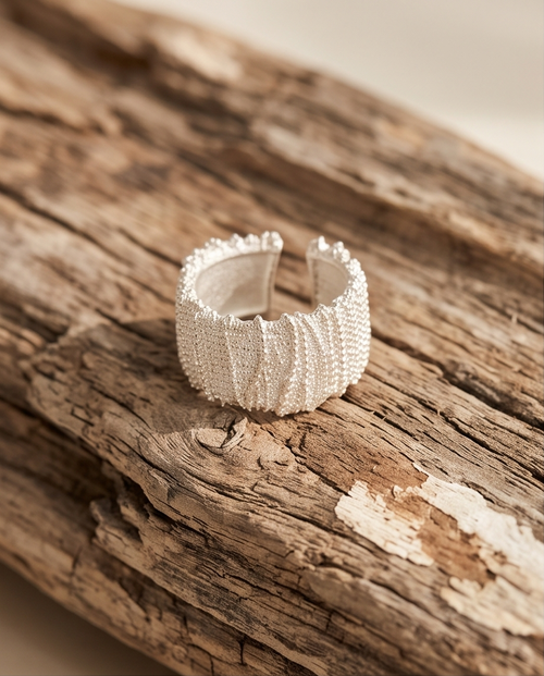 925 silver plated granular textured wide cuff open adjustable ring on green forest moss with smooth pebbles — nature editorial macro product shot showing full granular bead texture and scalloped edge