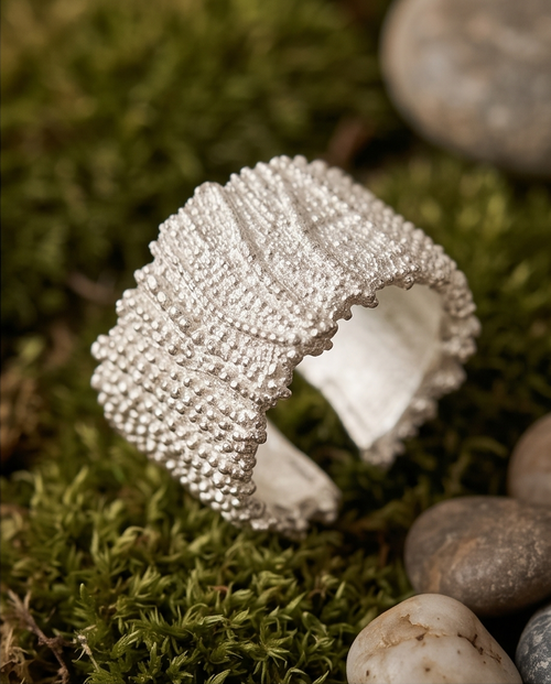 Model's hand in cream linen sleeve resting on dried pampas grass wearing 925 silver plated granular textured wide cuff open adjustable ring — warm bohemian lifestyle editorial