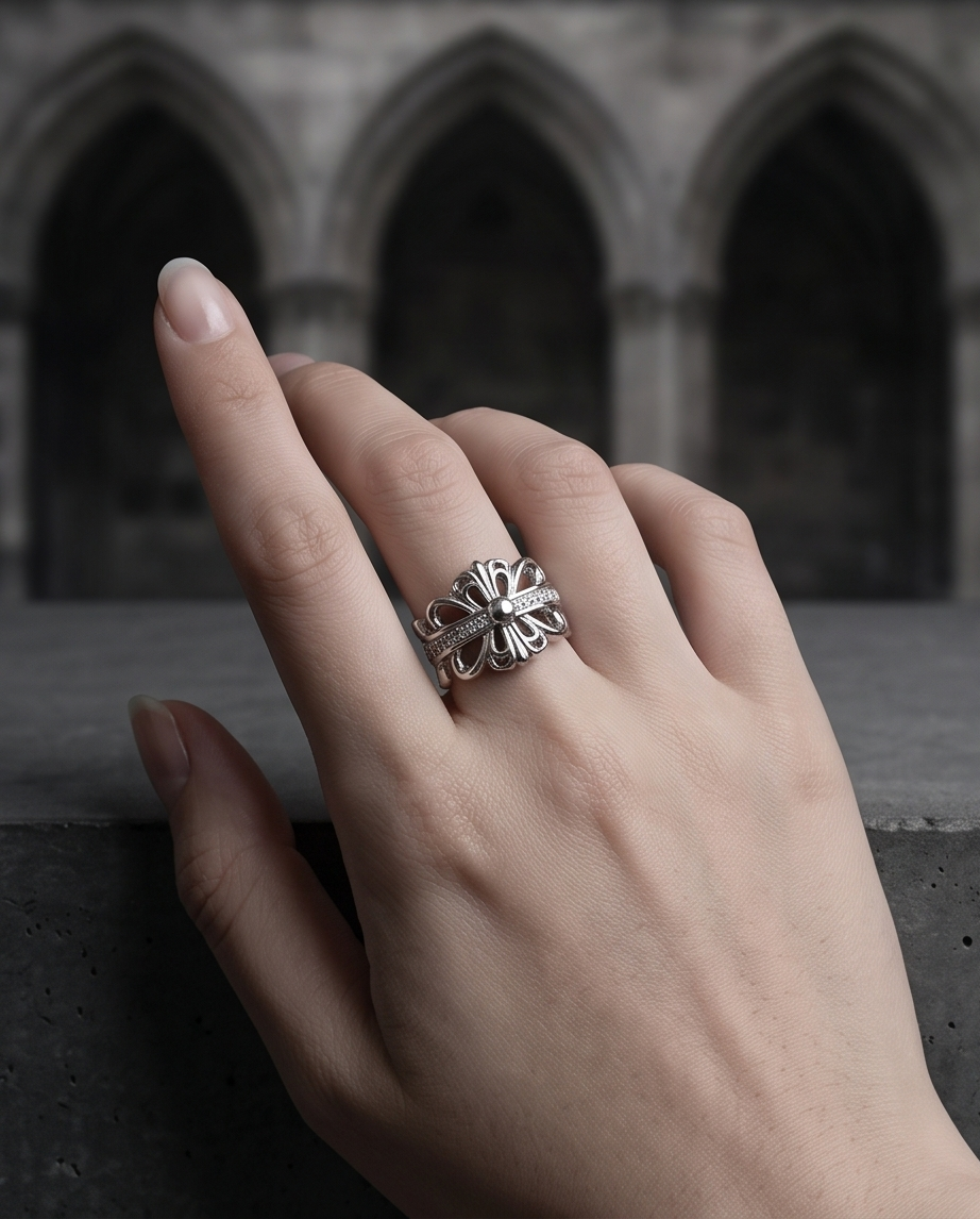 Extreme macro close up of silver plated gothic fleur de lis baroque cross CZ pave band open adjustable ring on dark slate rock showing filigree fleur de lis petals, CZ pave cross bar and polished bead centre in dramatic chiaroscuro light
