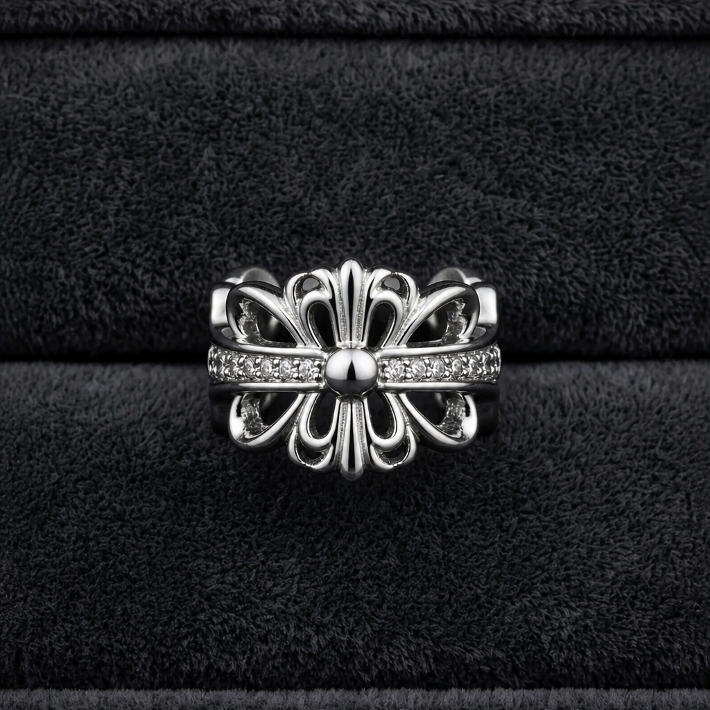 Silver plated gothic fleur de lis baroque cross CZ pave band open adjustable ring face-up on dark charcoal velvet ribbed fabric showing full fleur de lis silhouette and CZ pave cross band from above
