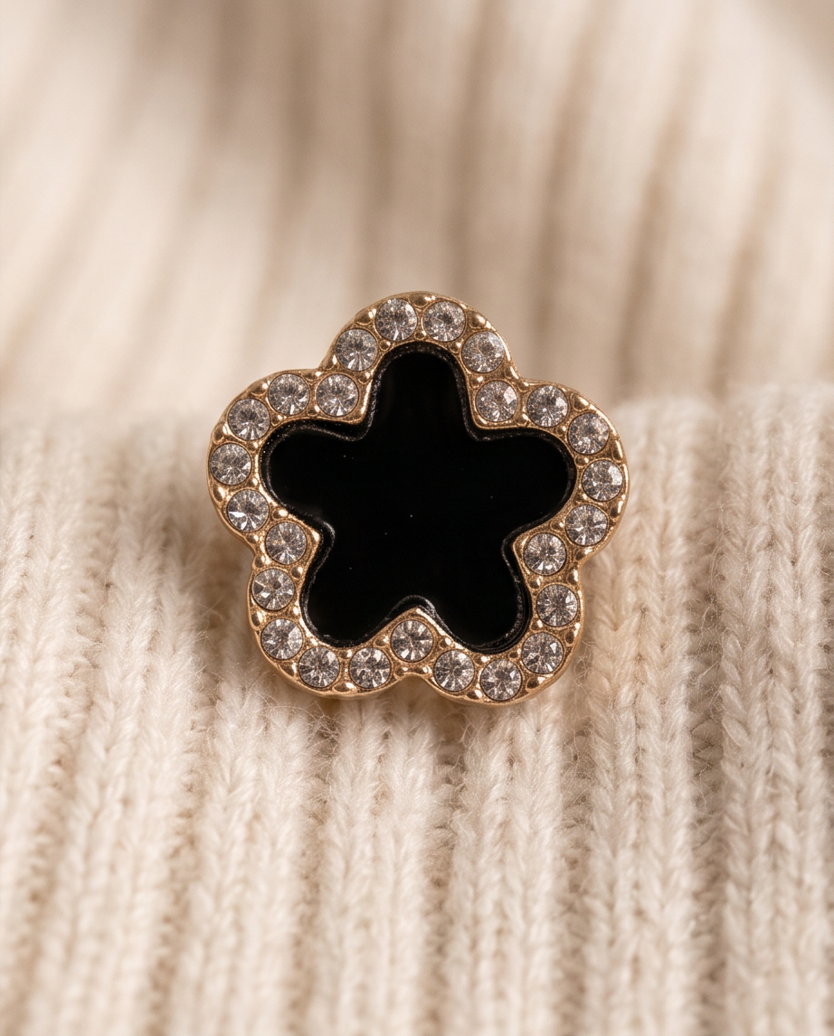Gold tone black enamel clover CZ pave stud earrings displayed in grey velvet jewellery box tray with draped blush satin ribbon — luxury gift presentation editorial