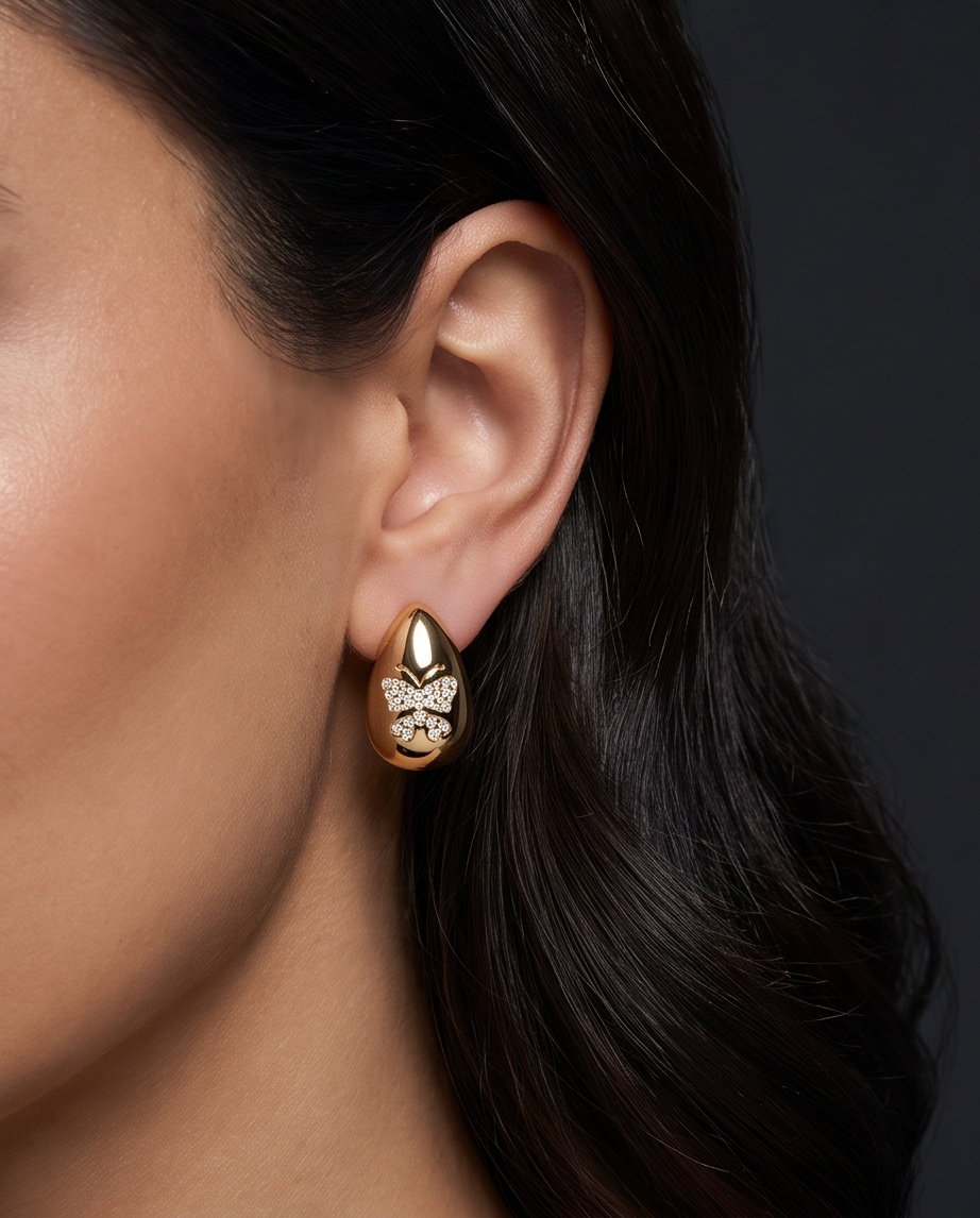 Gold Puffed Teardrop Butterfly Pavé Earrings - styled on model with dark hair, close-up ear shot against dark background