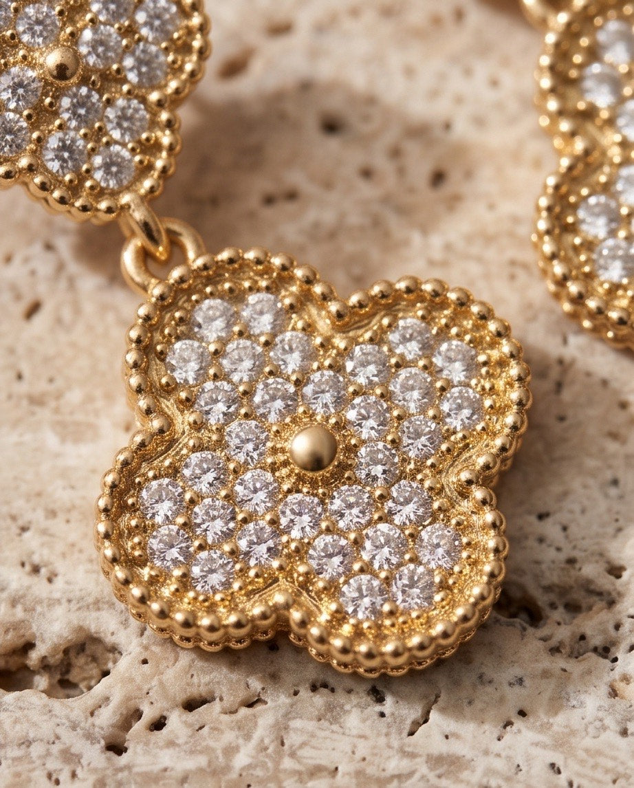 Macro close-up of gold pavé crystal clover pendant showing beaded milgrain edge and round brilliant crystal pavé with central gold stud
