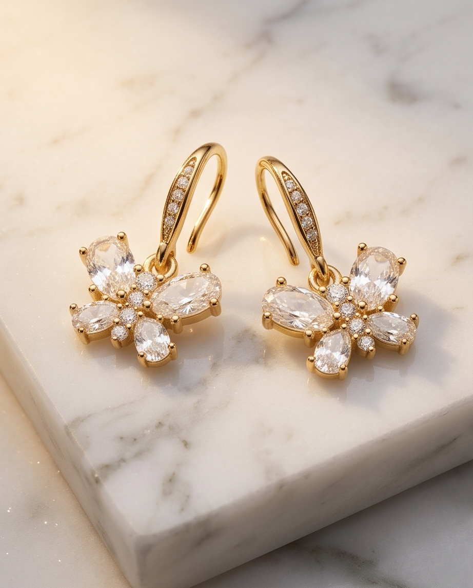 Butterfly crystal drop earrings on a marble tray beside a perfume bottle