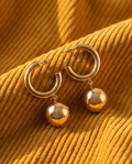 Gold hoop and ball drop earrings on corduroy fabric