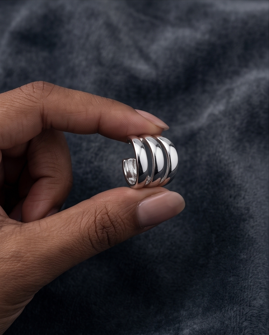 Silver triple band chunky hoop earring held in hand against grey fabric