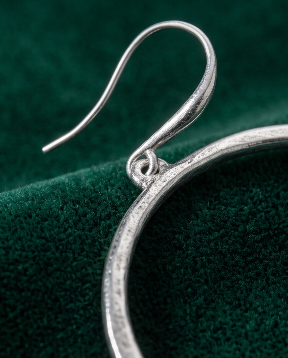 Silver brushed open circle drop earring close-up hook detail on green velvet