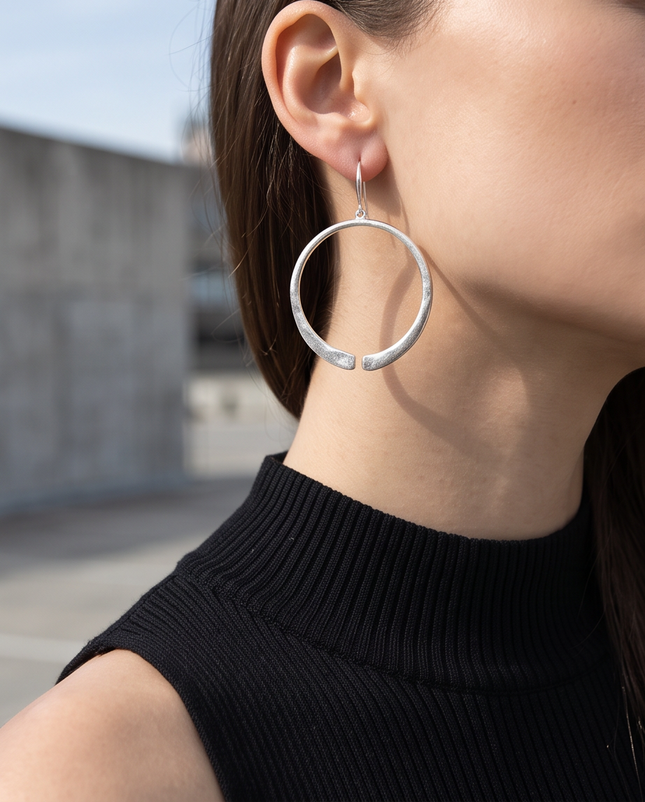 Silver open circle drop earring worn on model with black turtleneck