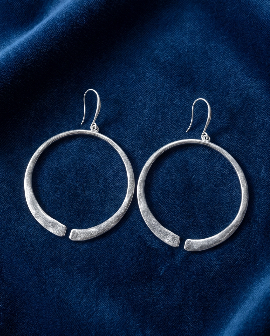 Silver open circle drop earrings flat lay on blue velvet