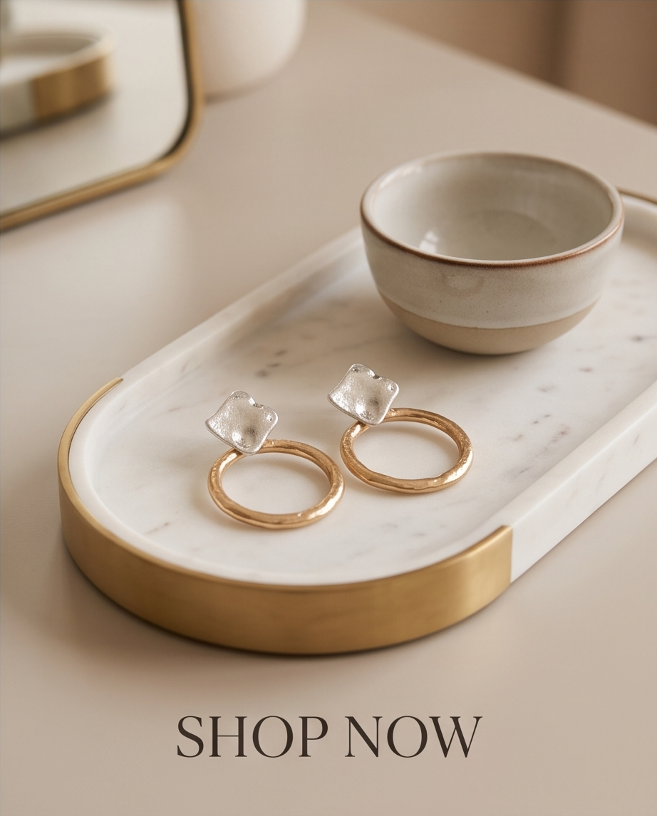 Two-tone square and hoop earrings styled on a marble tray