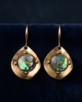 Close-up of green and violet iridescent centre in gold-tone drop earring