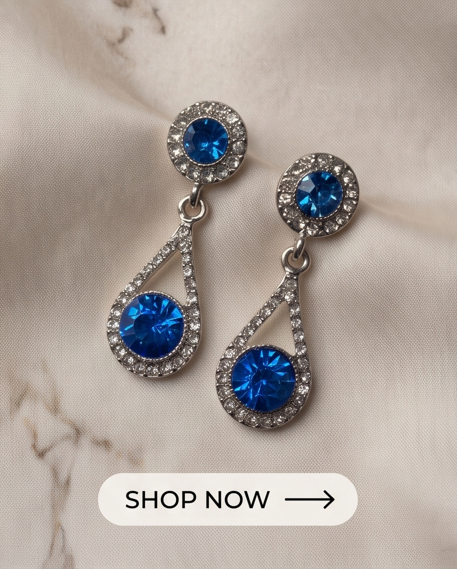 Pair of sapphire-blue teardrop earrings with silver-tone settings on mirror