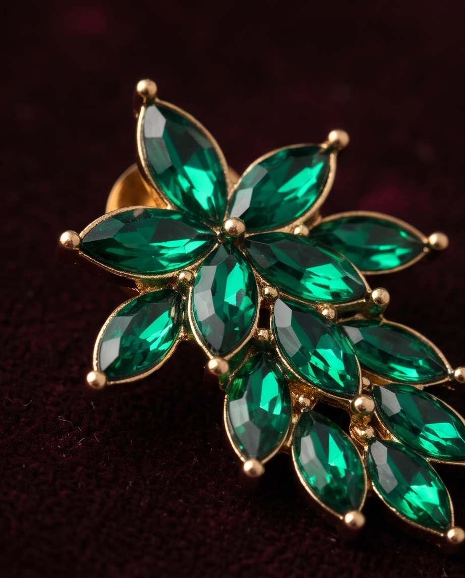 Pair of emerald green floral drop earrings on burgundy velvet