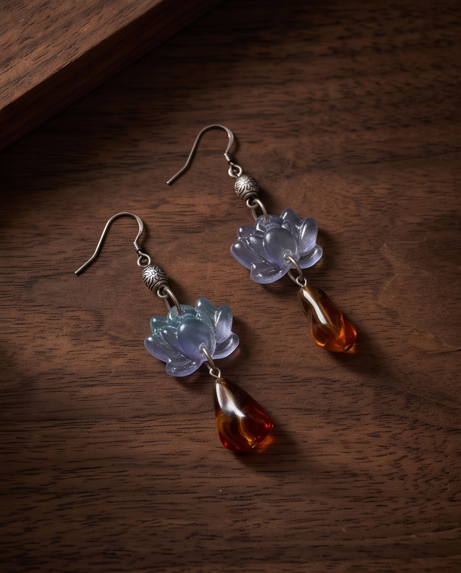 Pair of lilac lotus and amber-effect hook drop earrings angled on wood