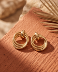 Pair of layered circle gold-tone drop earrings on terracotta surface