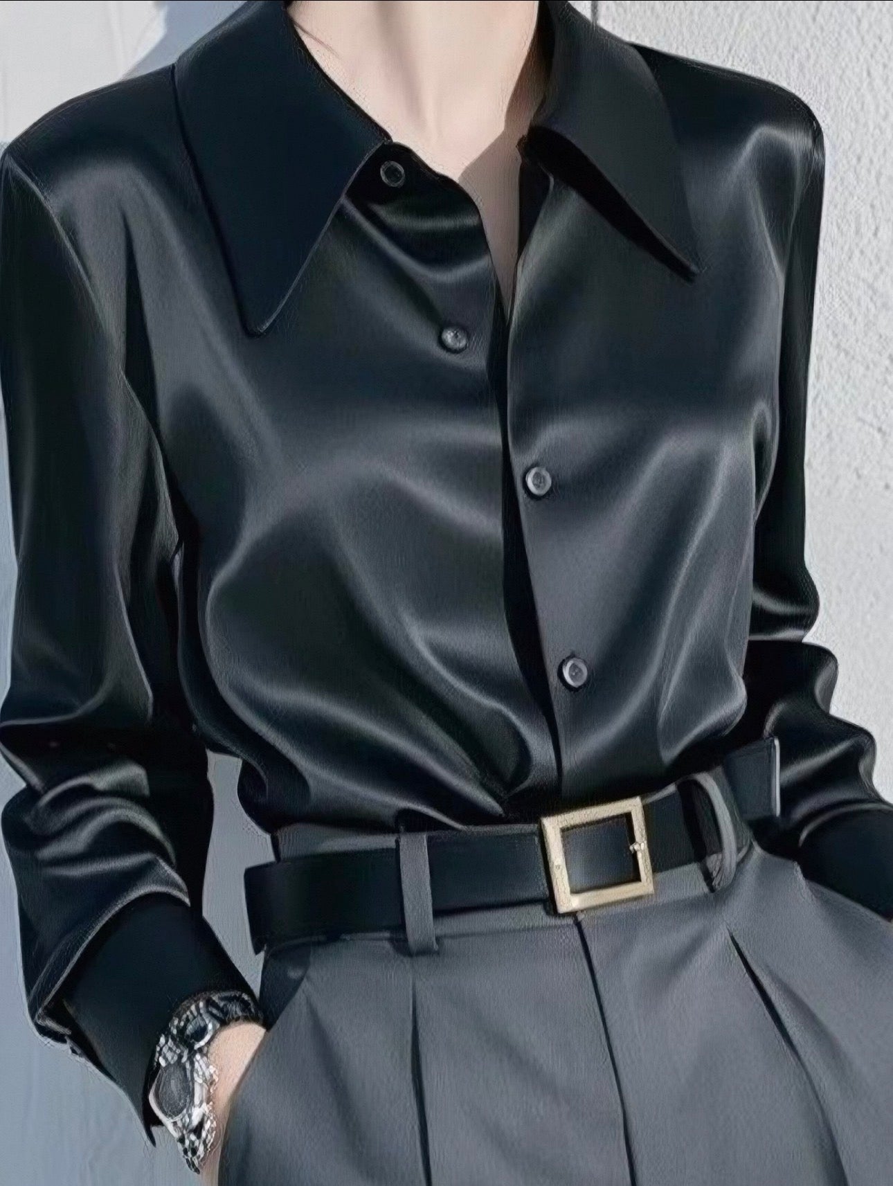 Black leather shirt with a belt and gray pants on a plain background