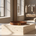 Brown leather belt with a gold buckle on a stone surface, sunlit room background