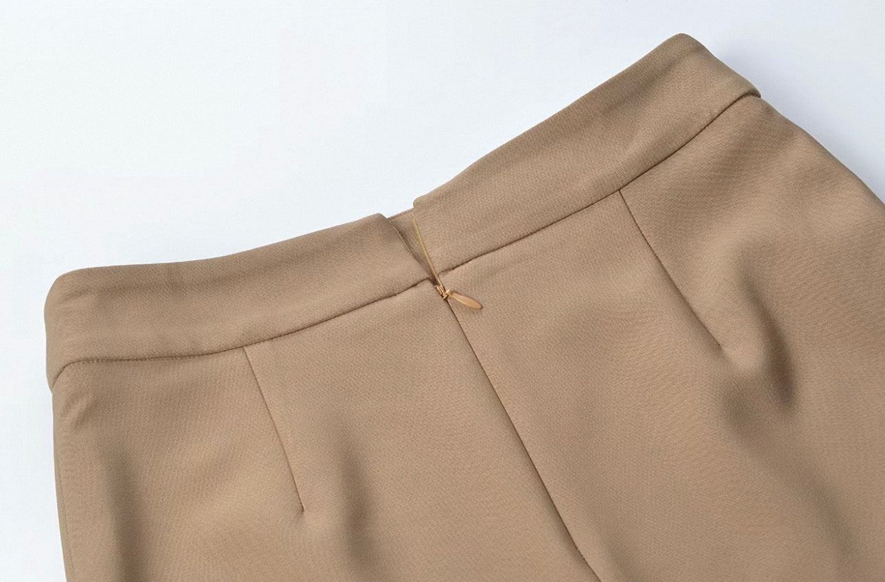 Close-up of a pair of tailored trousers in a warm taupe-beige color, showing the waistband, front seam, and fabric texture against a plain white background.