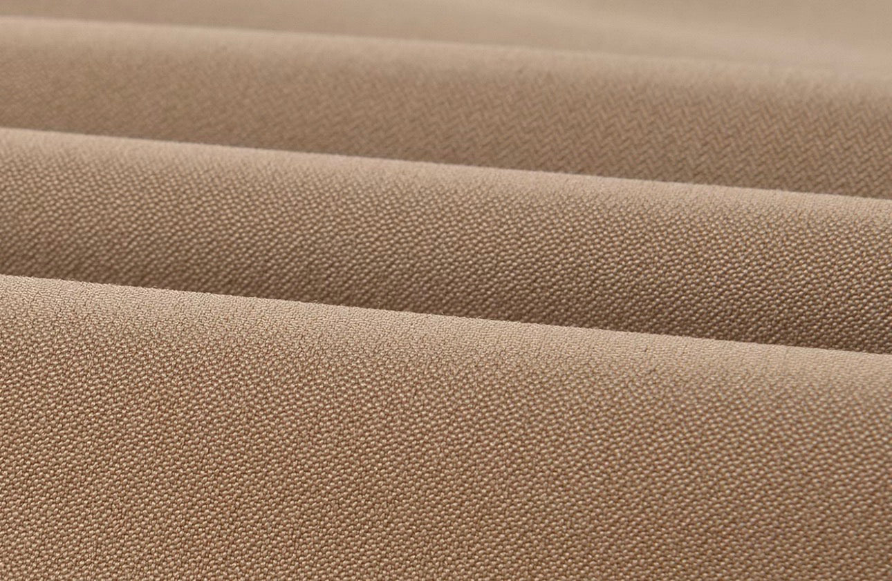 Close-up of a beige woven fabric with a fine textured surface, showing soft horizontal folds.