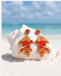 Goldfish beaded drop earrings on blue and white striped beach towel with straw hat and summer drink