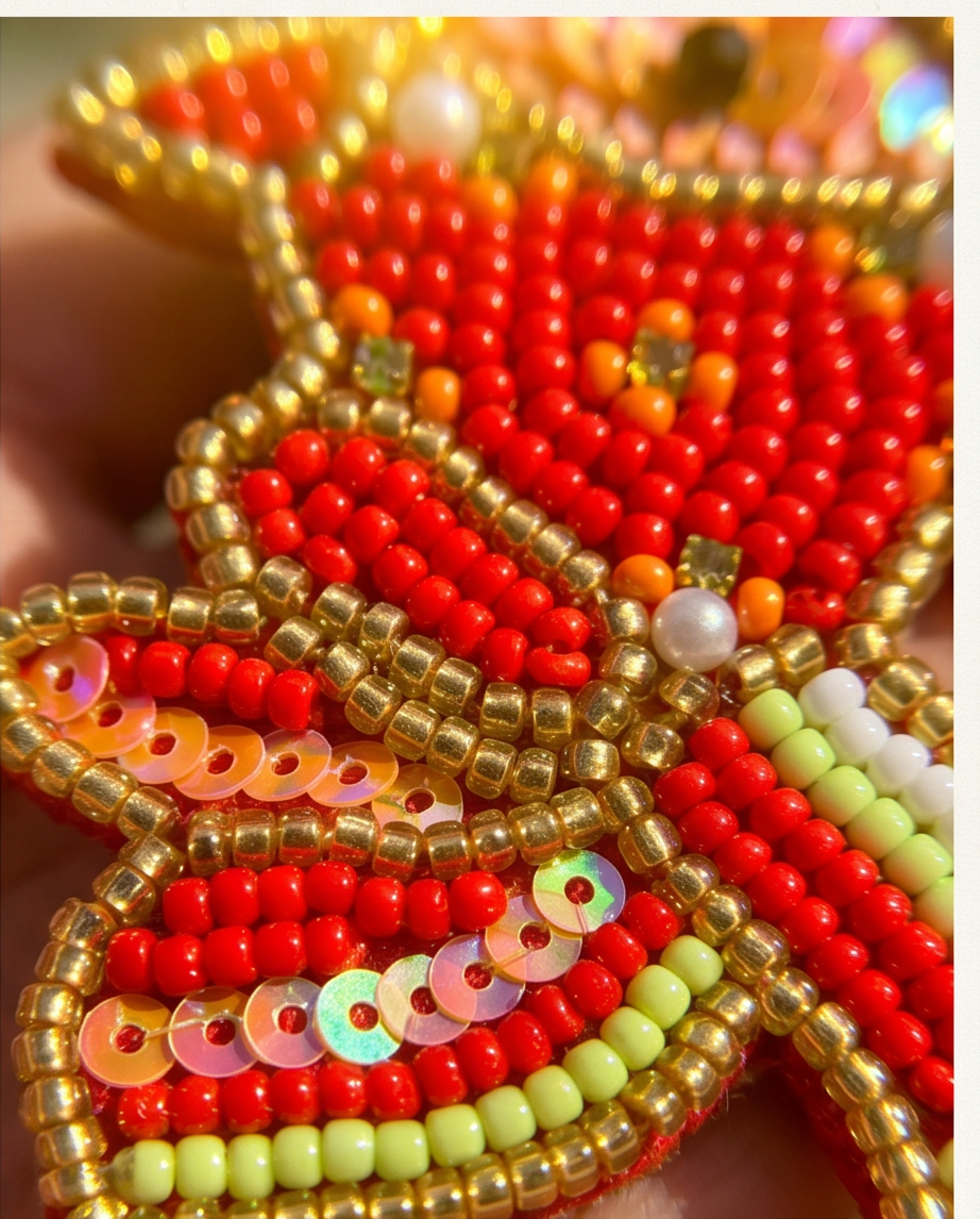 Model holding goldfish beaded drop earrings against tropical palm tree background