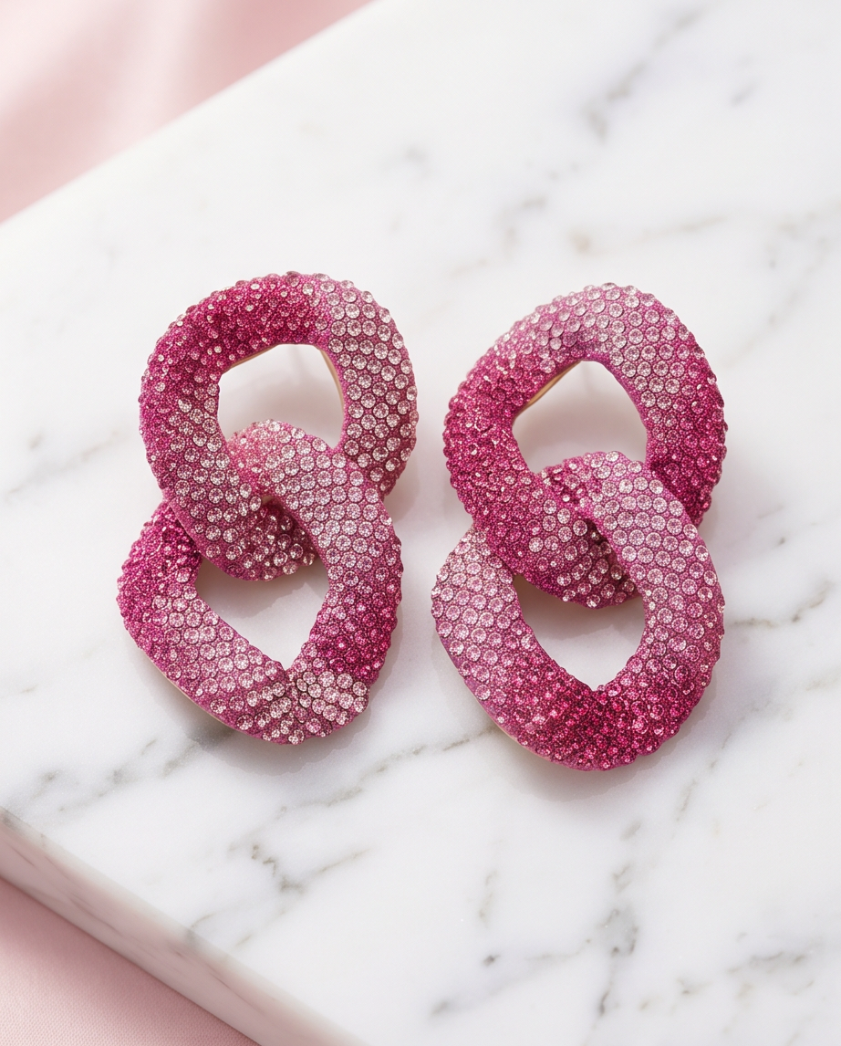 Pink crystal pavé chain link drop earrings on marble surface