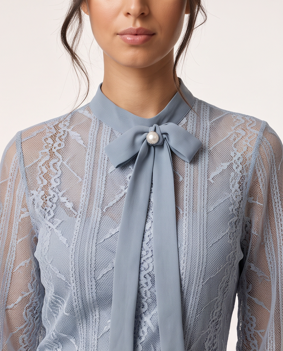 A close-up of a model wearing a light blue lace blouse with a matching fabric bow tie at the collar, accented by a small pearl-like center detail.