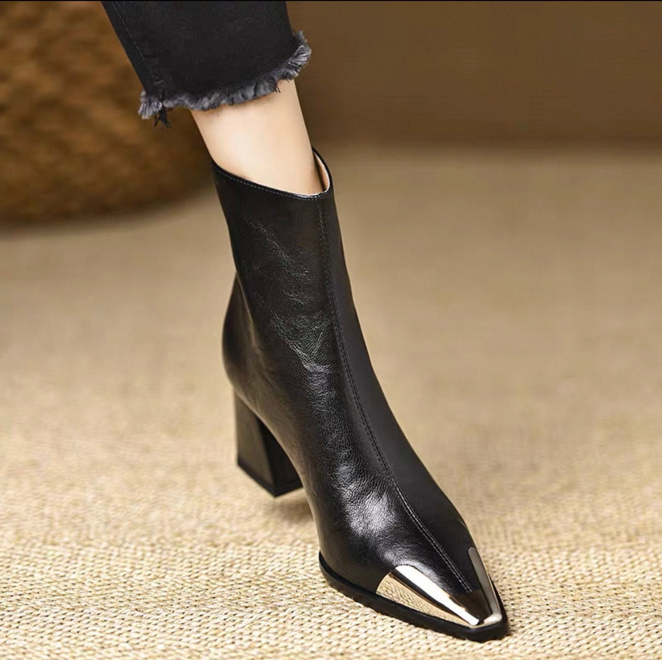 Black genuine leather metal cap-toe ankle boot — lifestyle side view on model