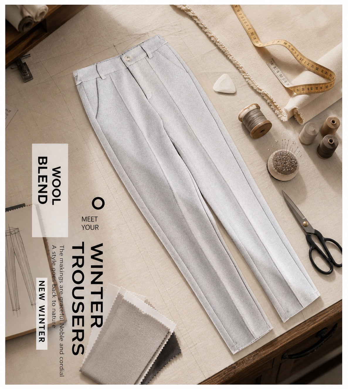 Light gray tailored trousers laid flat on a sewing-table surface with fabric swatches, scissors, thread, pins, and a measuring tape around them. Text on the image reads 'WOOL BLEND', 'MEET YOUR WINTER TROUSERS', and 'NEW WINTER'.