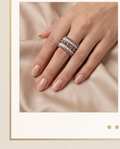 Model wearing pearl and silver bead stacked ring set on silk fabric