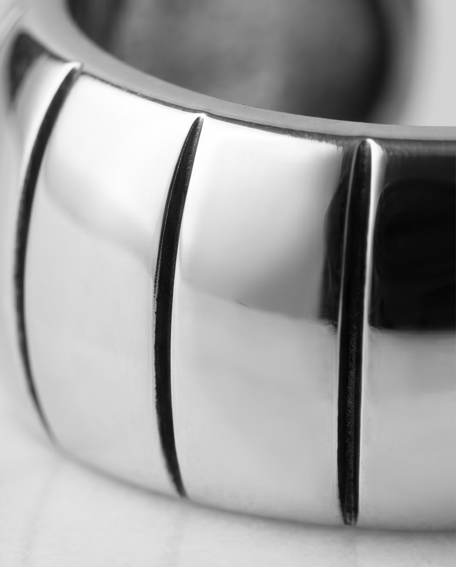Macro close-up of deep vertical groove detailing on silver chunky wide band ring