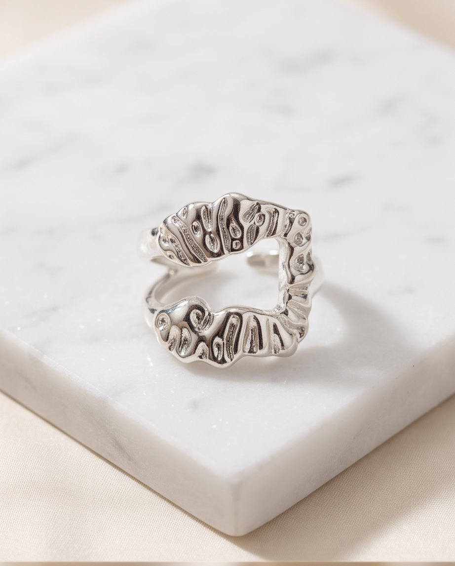 Silver sculptural open wrap ring on marble display block