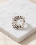 Silver sculptural open wrap ring on marble display block