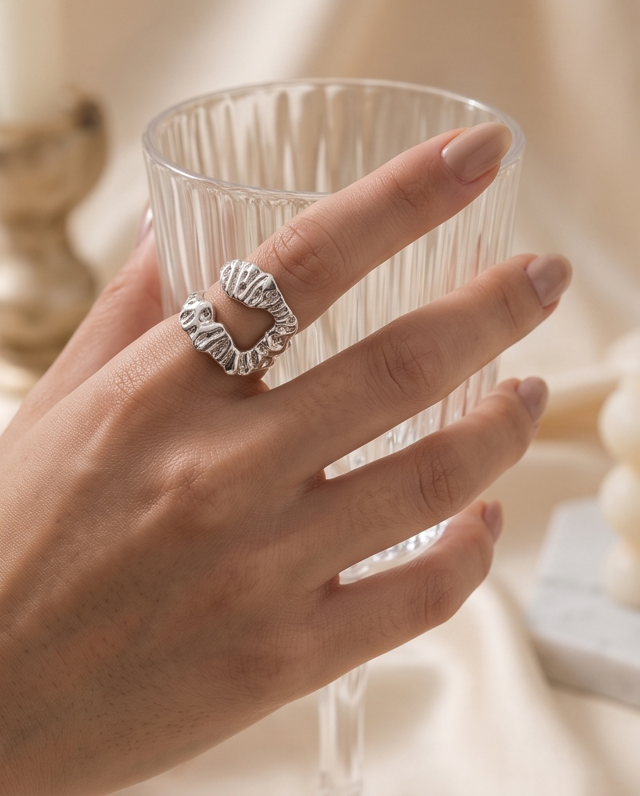 Silver sculptural open wrap ring on marble block angled view