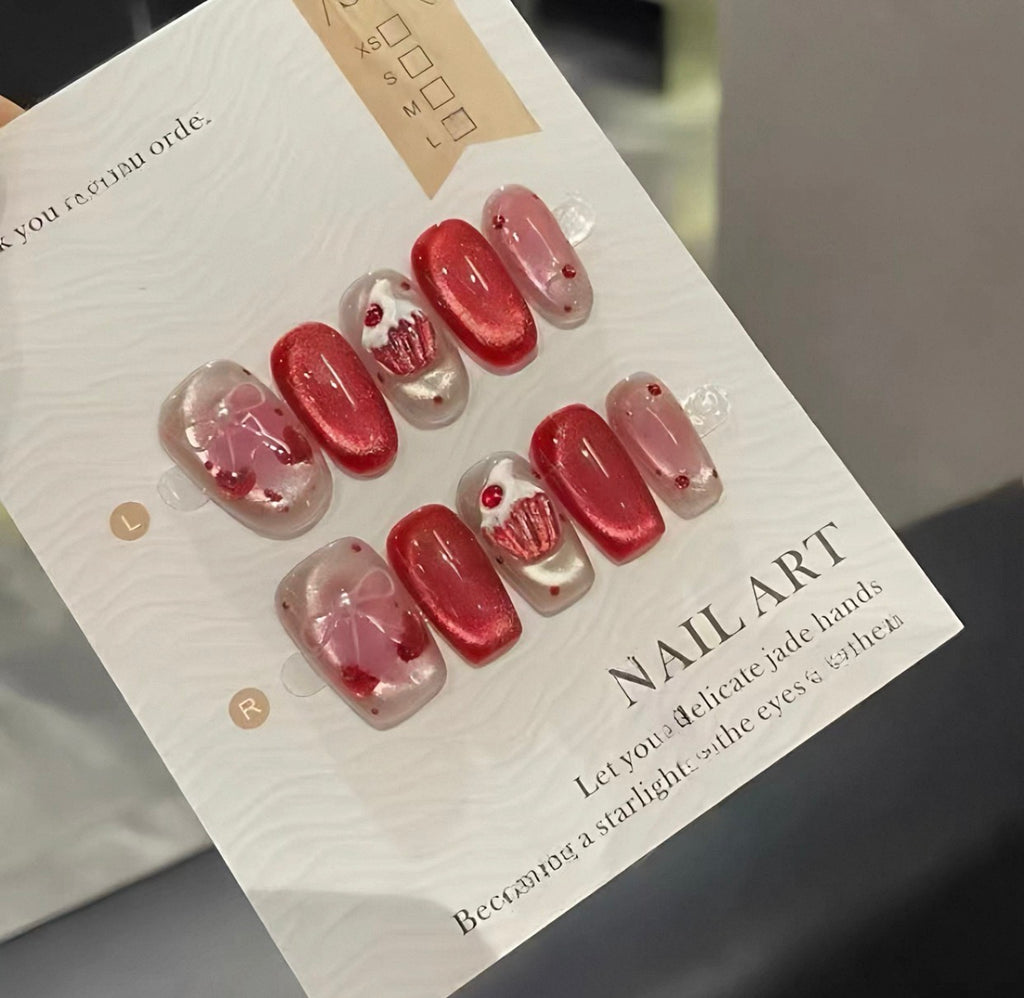 Red cupcake press-on nails worn on hand holding luxury bag