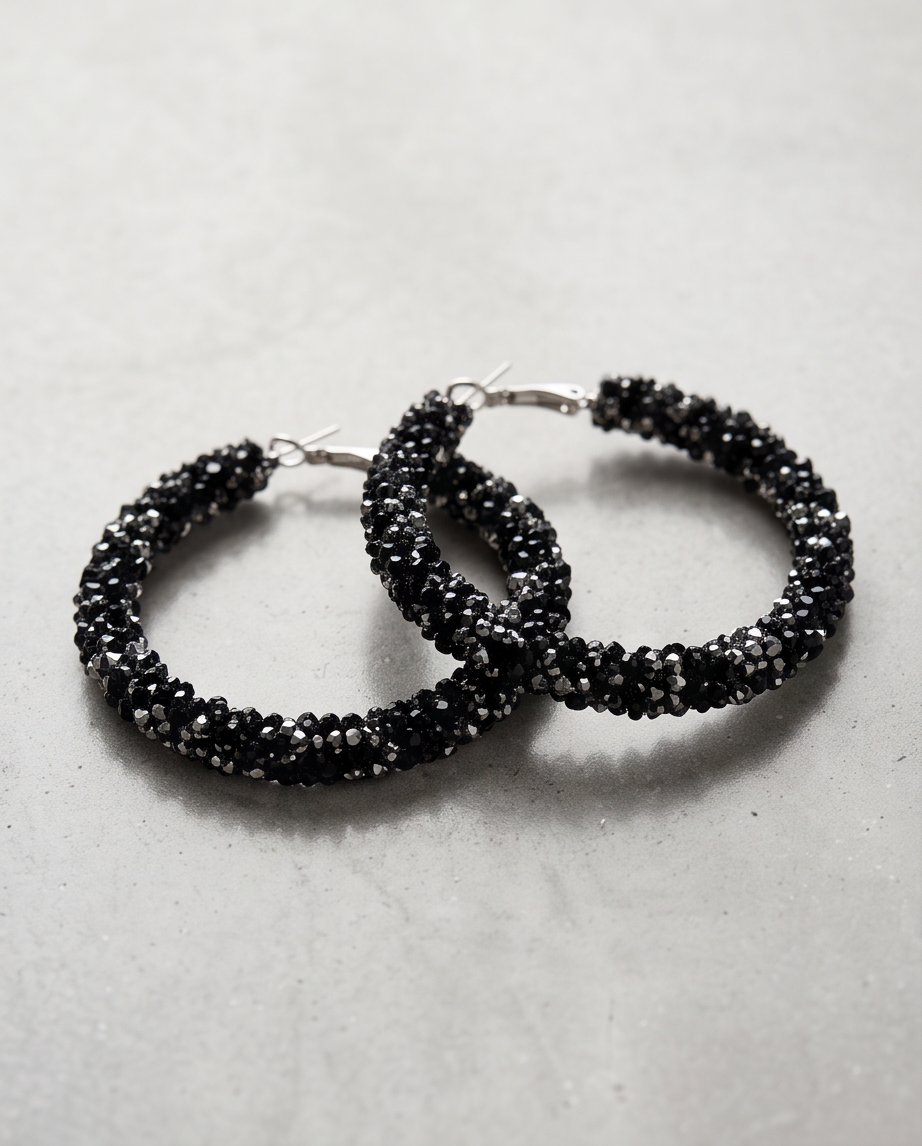 Sparkling black pavé crystal hoop earrings pair on grey stone surface