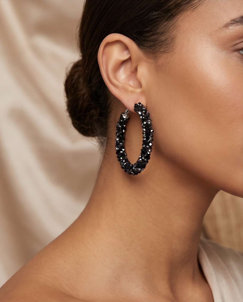 Sparkling black pavé crystal hoop earrings worn by model against satin background
