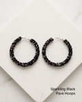 Sparkling black pavé crystal hoop earrings flat lay on white marble block
